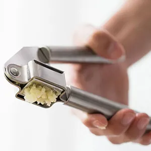 Stainless steel garlic press detail showing fresh minced garlic squeezed out easily.