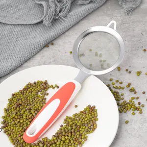 Close-up detail of stainless steel mesh strainer with red handle, ideal for kitchen baking.