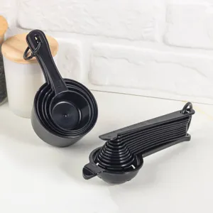 Vue détaillée de l'ensemble de tasses et cuillères à mesurer en plastique noir pour cuisine.