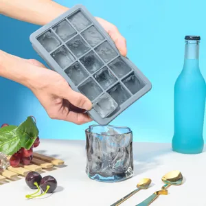 Détail du bac à glaçons en silicone 15 grilles montrant le moule flexible libérant de la glace.