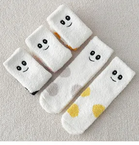 Dicke Korallenfleece-Schlafsocken mit süßen bestickten Smiley-Gesichtern und weicher Textur.