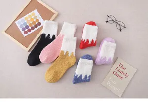 Detail shot of cozy winter fuzzy coral fleece socks with colorful contrast design for home.