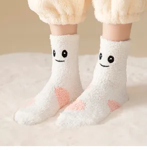 Nahaufnahme kuscheliger Korallenfleece-Schlafsocken mit gesticktem süßem Gesicht und Plüsch.