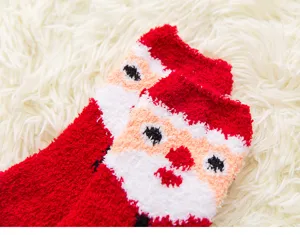 Close-up detail of cozy red coral fleece Christmas Santa socks on soft white blanket background.