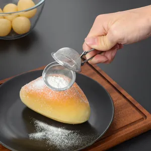Stainless steel mini mesh tea infuser and powder sifter detail showing hand using handle.