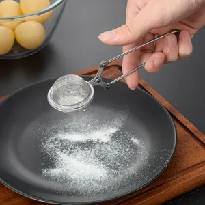 Stainless steel tea infuser close up showing fine mesh design and squeeze handle in use.