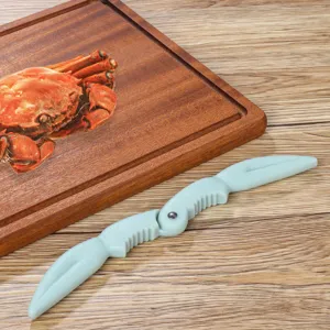 Détail de l'outil ouvre-crabe en plastique bleu clair avec un design de pince unique.