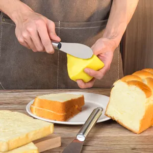 Detailaufnahme des Butterbuntmessers aus Edelstahl beim Streichen auf frischem Toastbrot.
