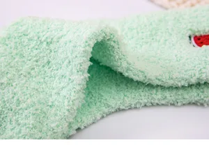 Detailed view of thick fuzzy coral fleece sleep socks in light green with cute fruit embroidery.