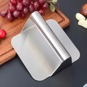 Stainless steel burger press detail view, manual meat smasher and dough scraper for cooking.