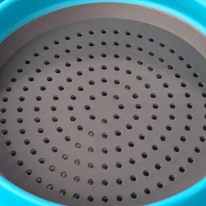 Gros plan sur le fond de la passoire pliante, montrant des trous de drainage et du plastique.
