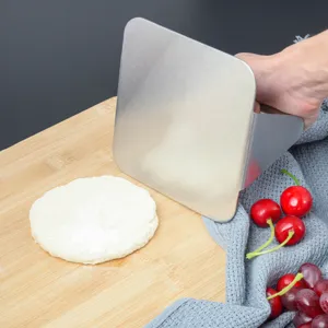 Stainless steel burger press detail, hand holding meat press tool on wooden cutting board.