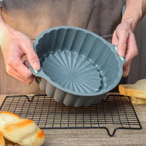 Detailed shot of grey silicone cake mold with green handles, showcasing fluted interior.