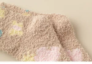 Close-up detail of fluffy coral fleece winter warm socks with soft tulip floral pattern texture.