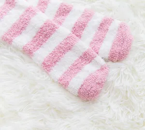 Close-up detail of soft fluffy pink and white striped coral fleece fuzzy socks texture.