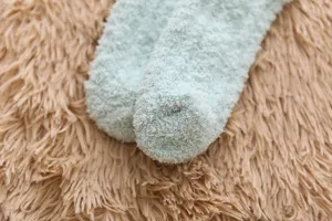 Close-up detail of soft fluffy winter cozy sleep socks in light green texture view.