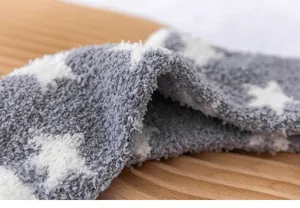 Gros plan détaillé de chaussettes d'hiver douces en polaire corail avec motif d'étoiles.