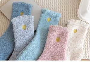 Close up of soft cozy coral fleece fuzzy socks with cute gold heart embroidery for warm winter.