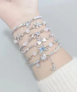 Detailed shot of layered handmade woven bracelets with sparkling zircon charms, stars and moons.