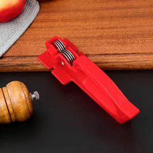 Detailed close-up view of a red manual kitchen knife sharpener with metal abrasive wheels.