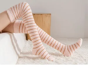 Close-up detail of cozy striped fluffy coral fleece over-the-knee socks for winter home wear.