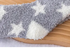 Gros plan de chaussettes d'hiver douillettes en polaire corail grise avec motif d'étoiles.