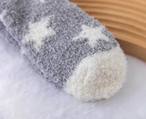 Gros plan détaillé de chaussettes duveteuses en polaire corail d'hiver avec motif étoile.