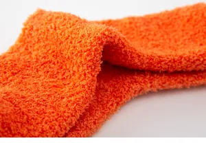 Gedetailleerd close-up overzicht van de zachte oranje koraalvleece sokken stof textuur.