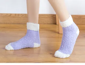 Close-up detail of winter thick fuzzy coral fleece sleep socks with color block design.