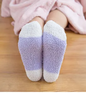 Close-up of cozy purple and white plush fuzzy socks, thick coral fleece for winter sleep.