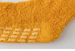 Close-up of fuzzy coral fleece thermal sock with non-slip sole grips for cozy home wear.
