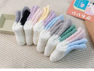 Close-up detail of soft coral fleece color-block fuzzy socks arranged on cozy knit blanket.
