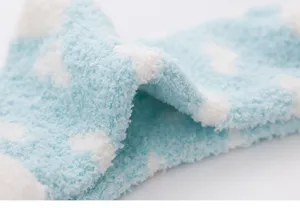 Primo piano texture calzini pile corallo inverno, blu con cuori bianchi, morbidi e caldi.
