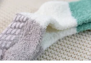 Close-up detail shot of thick plush winter socks, showing soft coral fleece texture and grip dots.