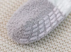 Close-up detail of winter thickened coral fleece fuzzy socks with anti-slip silicone grip soles.