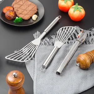 Détail de l'ensemble de spatules et pinces de cuisine en acier inoxydable pour cuire les steaks.