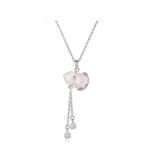Close-up of pink gourd pendant necklace with tassel and coin charms, delicate silver chain.