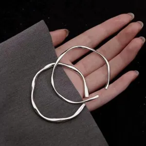 Gros plan détaillé des bracelets joncs ouverts argentés irréguliers de style minimaliste.