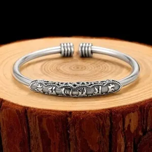 Bracelet manchette en argent vintage avec gravure de mantra et extrémités enroulées.