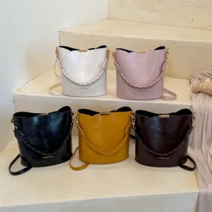Vue détaillée de sacs seau élégants en cuir PU de diverses couleurs avec poignées tressées.