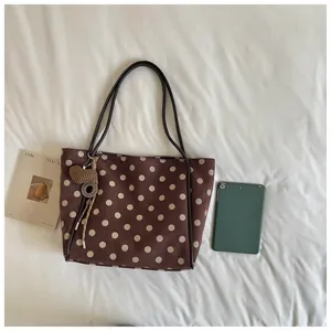 Brown polka dot tote bag detail, featuring large capacity, slim shoulder straps and stylish charm.
