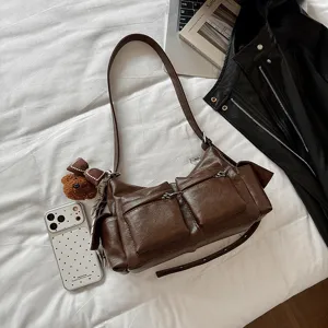 Detail view of stylish brown leather shoulder bag with multiple exterior zipper pockets.