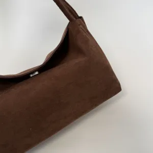 Nahaufnahme der braunen Wildleder-Umhängetasche, weiche Textur und schlichte Metallschließe.