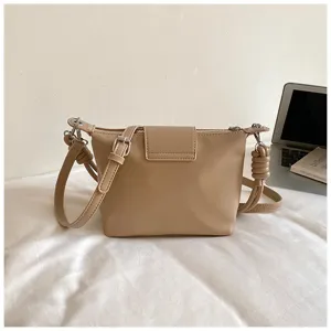 Detail view of khaki shoulder bag with side knot design and adjustable strap on white.