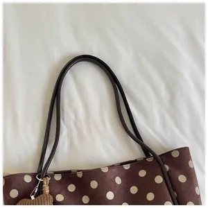 Close-up of brown polka dot tote bag detail, featuring dark shoulder strap and cute charm.
