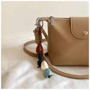 Detail shot of retro versatile women crossbody shoulder bag featuring colorful bead pendant decor.
