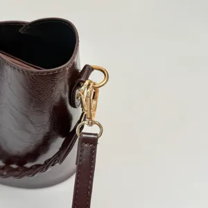 Gros plan détail sac seau marron foncé quaterie dorée boucle sangle texture cuir