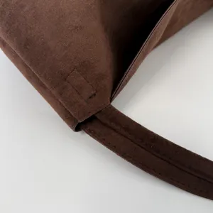 Nahaufnahme eines braunen Wildleder-Umhängetaschen-Details mit feinen Nähten und Riemen.