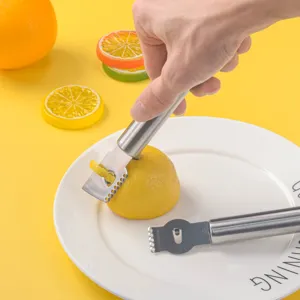 Primer plano de rallador de limón de acero inoxidable en uso, herramienta de cocina.