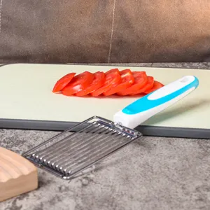 Close-up detail of stainless steel tomato slicer with non-slip handle and sliced tomatoes.